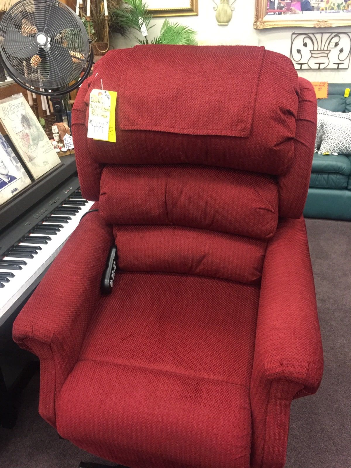 A red recliner is sitting next to a piano in a room.