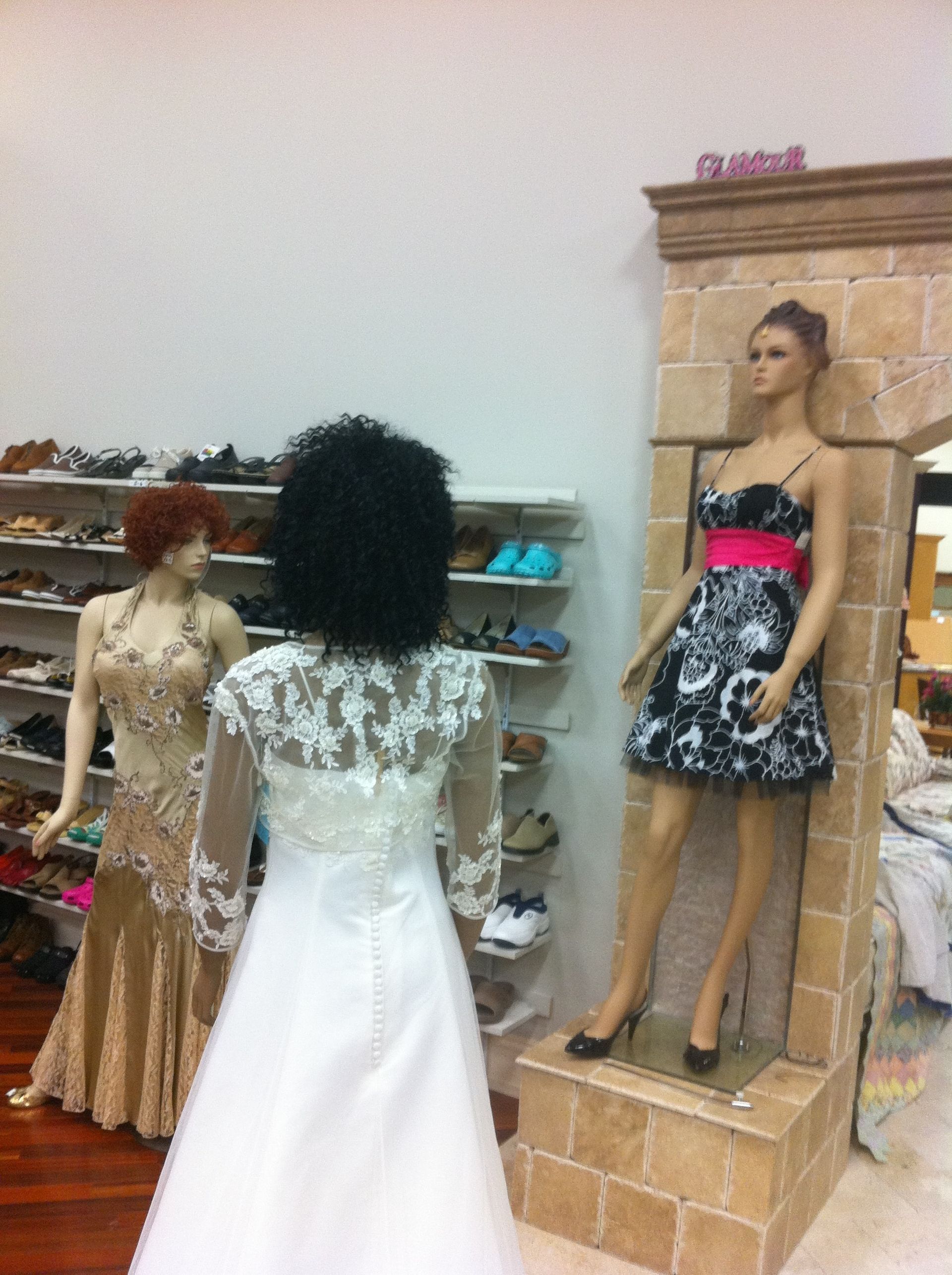 A woman in a wedding dress stands next to a mannequin
