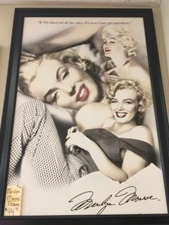 A framed picture of marilyn monroe is hanging on a wall.