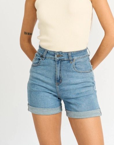 Mujer que viste pantalones cortos de mezclilla azul claro y una camiseta sin mangas de color crema