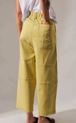 Persona que viste pantalones anchos de color amarillo, con bolsillos y pliegues.