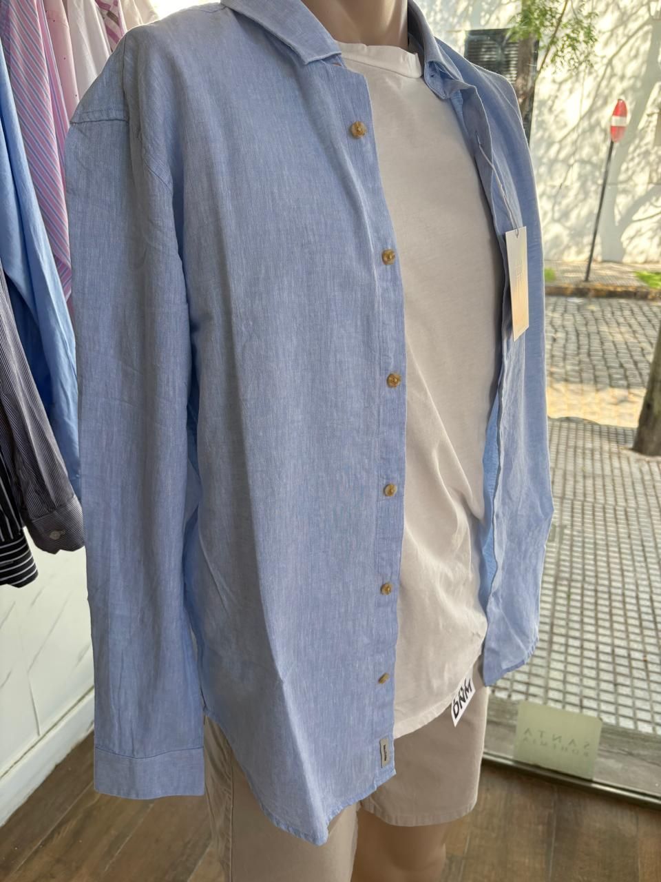 Maniquí con camisa azul, camiseta blanca y pantalón corto beige. Exhibido en una tienda.