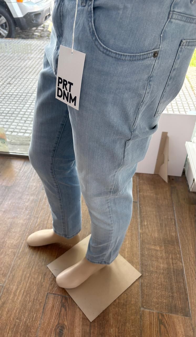 Pantalones vaqueros de mezclilla azul claro sobre un maniquí, con una etiqueta de precio de PRT DNM.