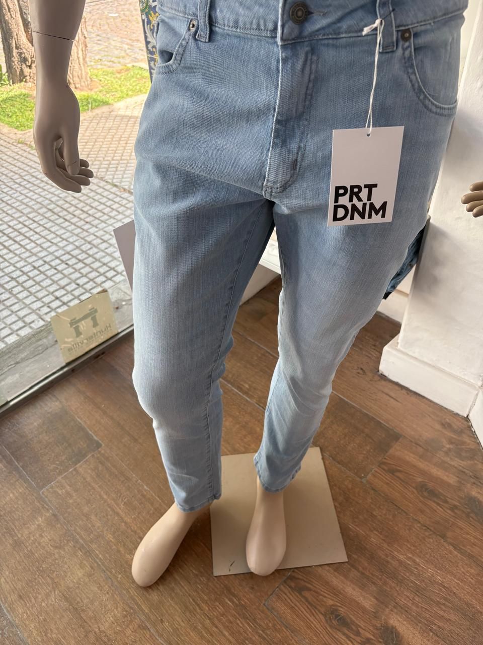 Pantalones vaqueros de mezclilla azul claro sobre un maniquí, con una etiqueta de precio de PRT DNM.