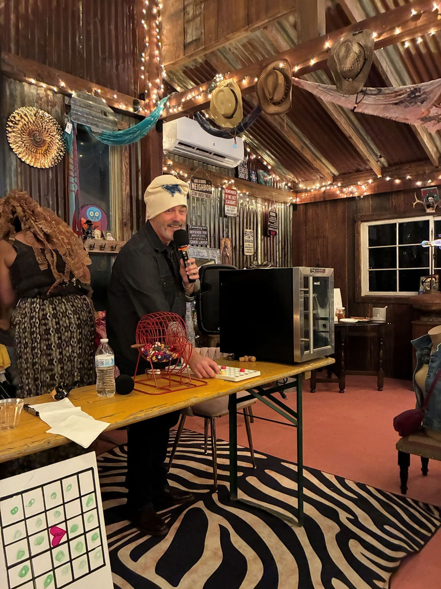 Person in a festive room stands behind a table with equipment on a zebra rug.