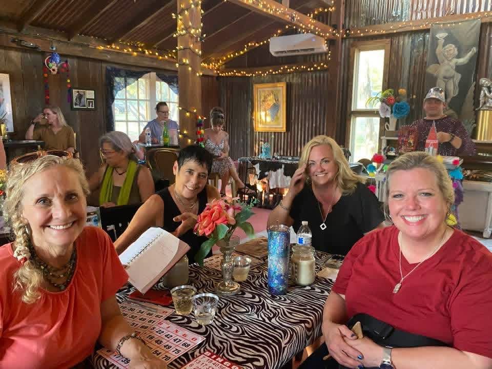Group seated at a rustic indoor gathering, smiling around a table with drinks and zebra-patterned decor