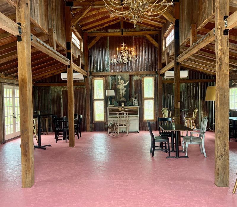 Rustic wooden hall with pink floor, chandeliers, and tables on either side of a central fireplace
