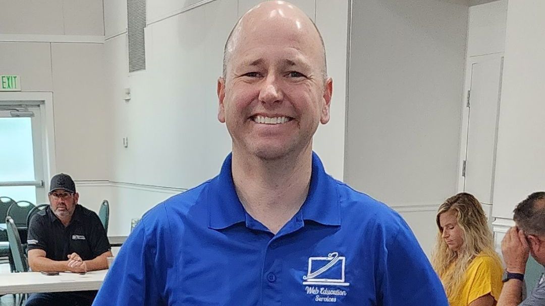 A man in a blue shirt is standing in a room with his hands on his hips.