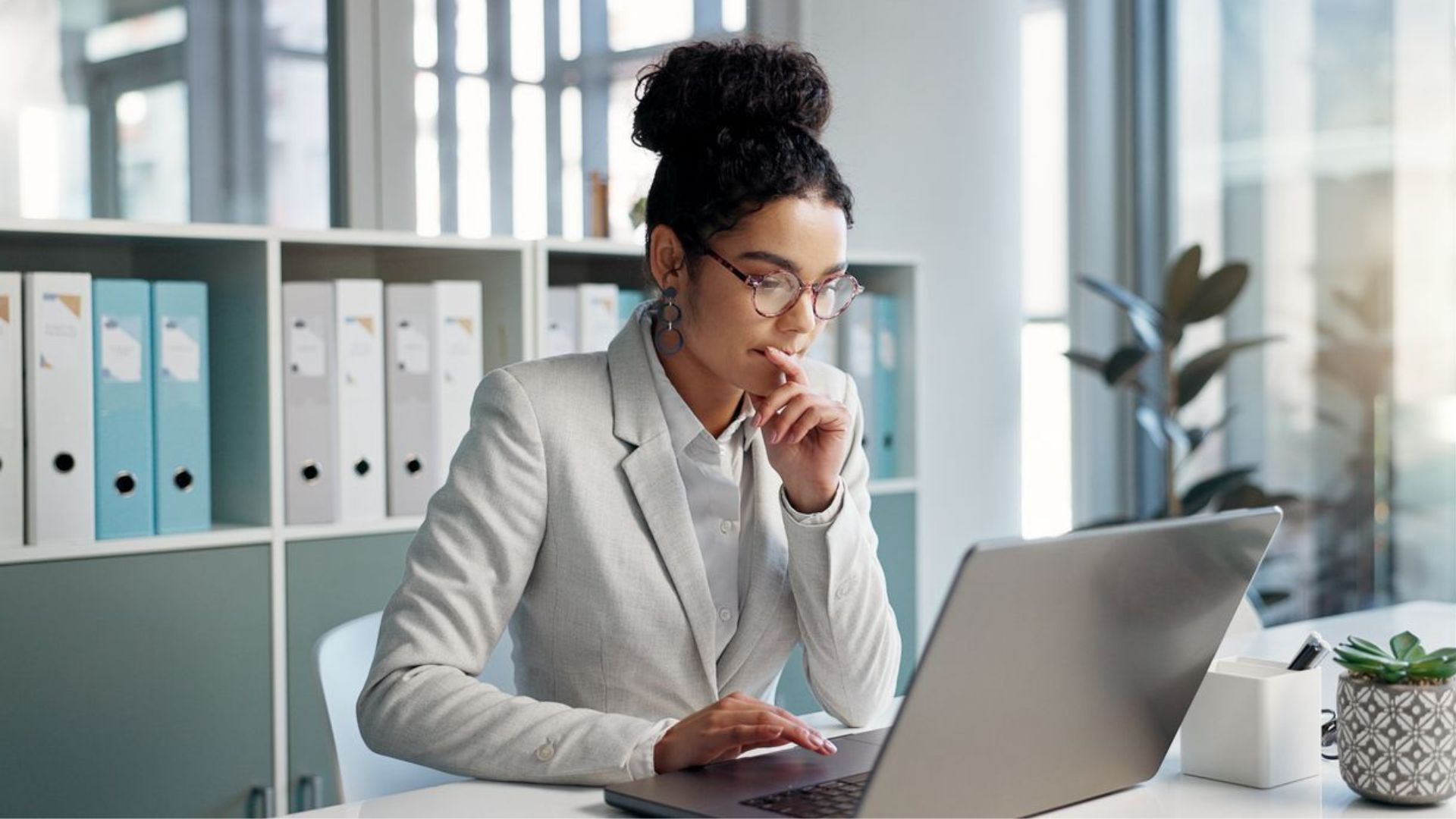 A woman is sitting at a desk using a laptop computer.