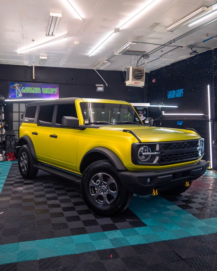 a yellow ford bronco is parked in a garage .