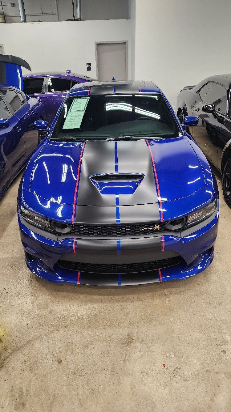a blue and black dodge charger is parked in a garage .