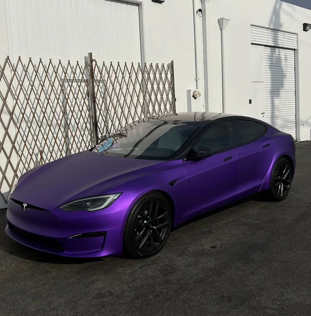 a purple tesla is parked in front of a white building