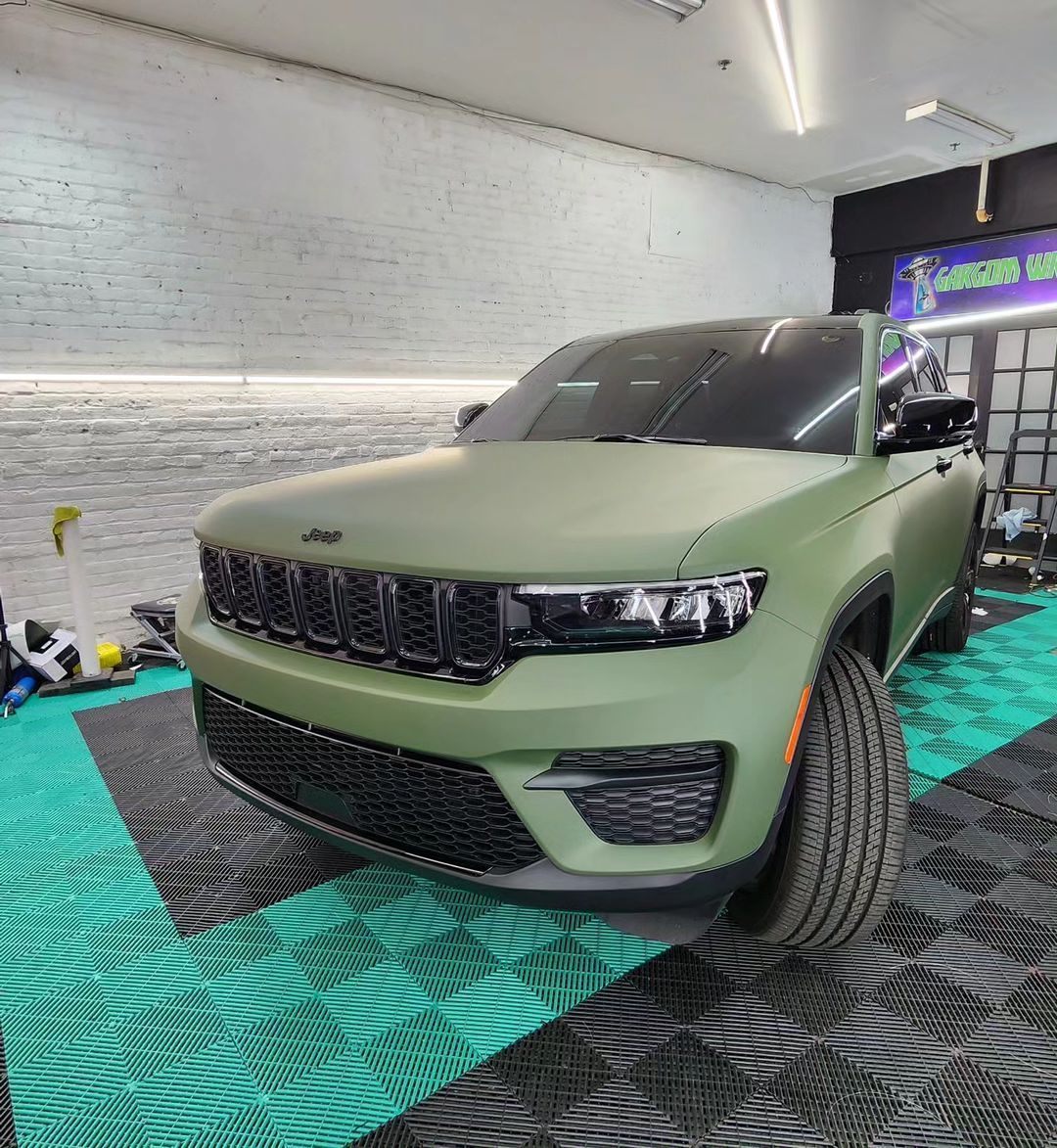 a green jeep is in a garage with a sign that says car wizard