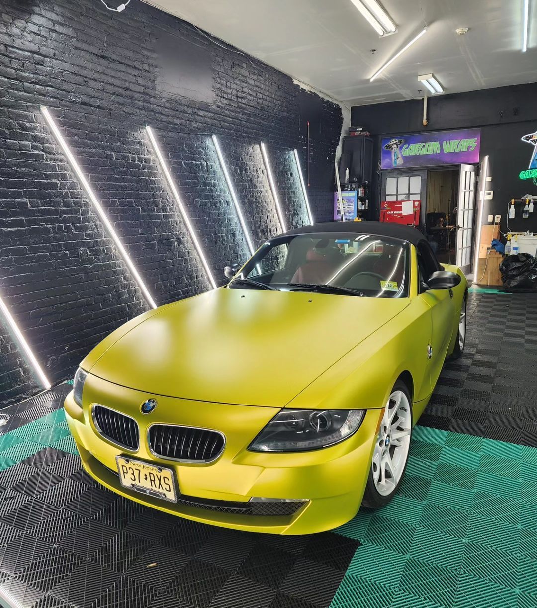 a yellow car is parked in a garage with a sign that says green wraps