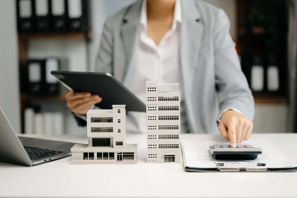 A woman is sitting at a desk using a calculator and a tablet.