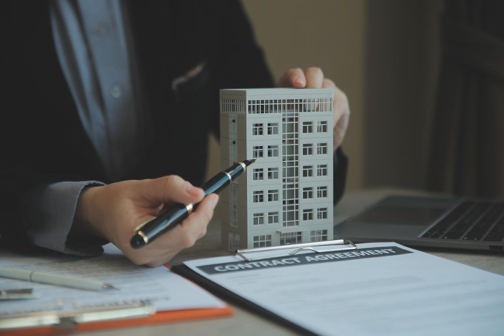 A man is holding a pen and a model of a building.