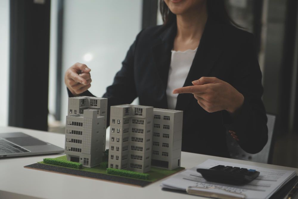 A woman is sitting at a table with a model of a building.
