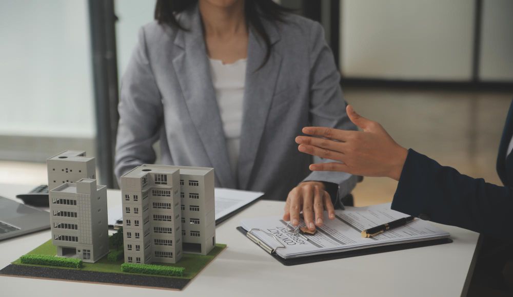A man and a woman are sitting at a table with a model of a building.