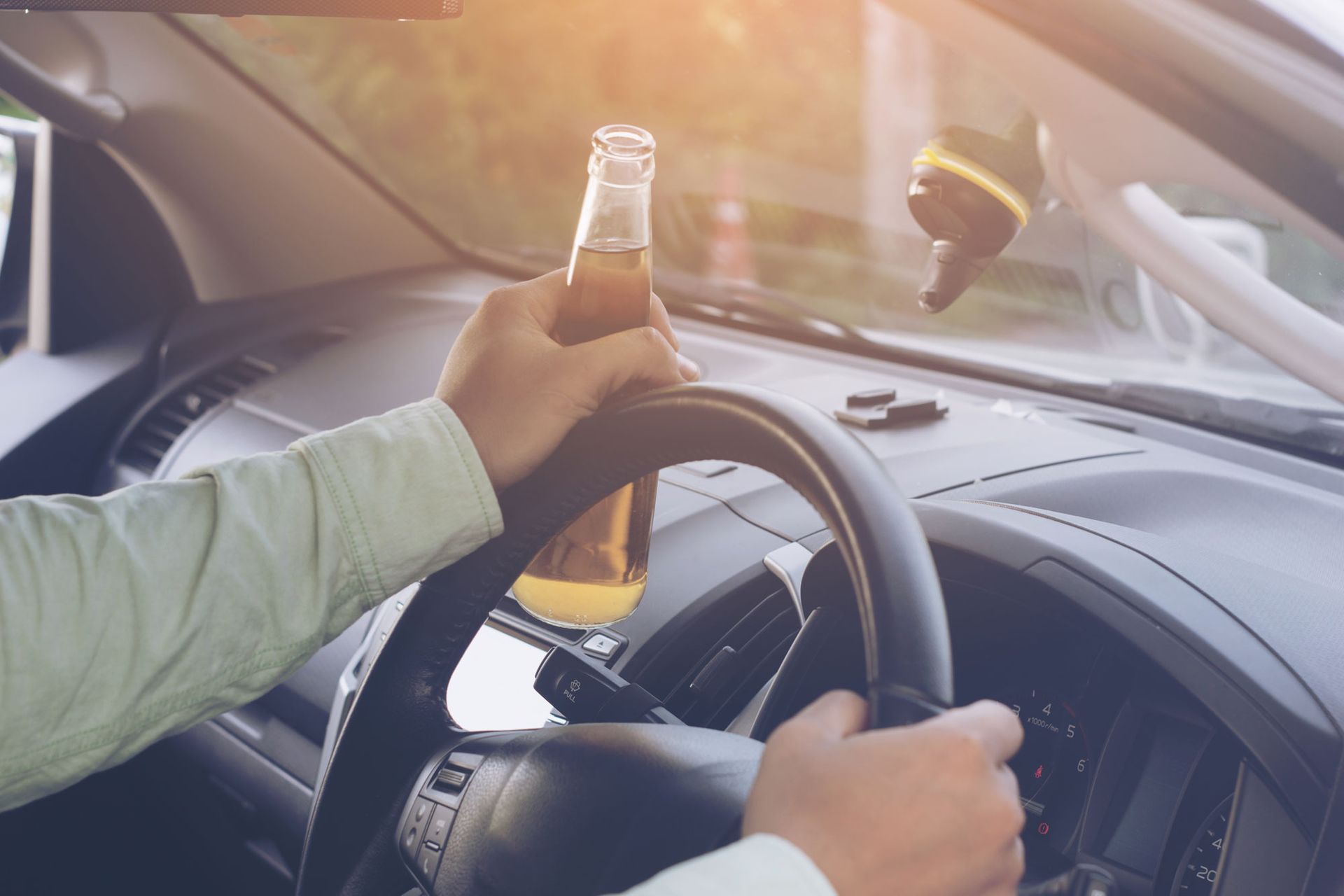 Drunk man drives a car with a bottle of beer