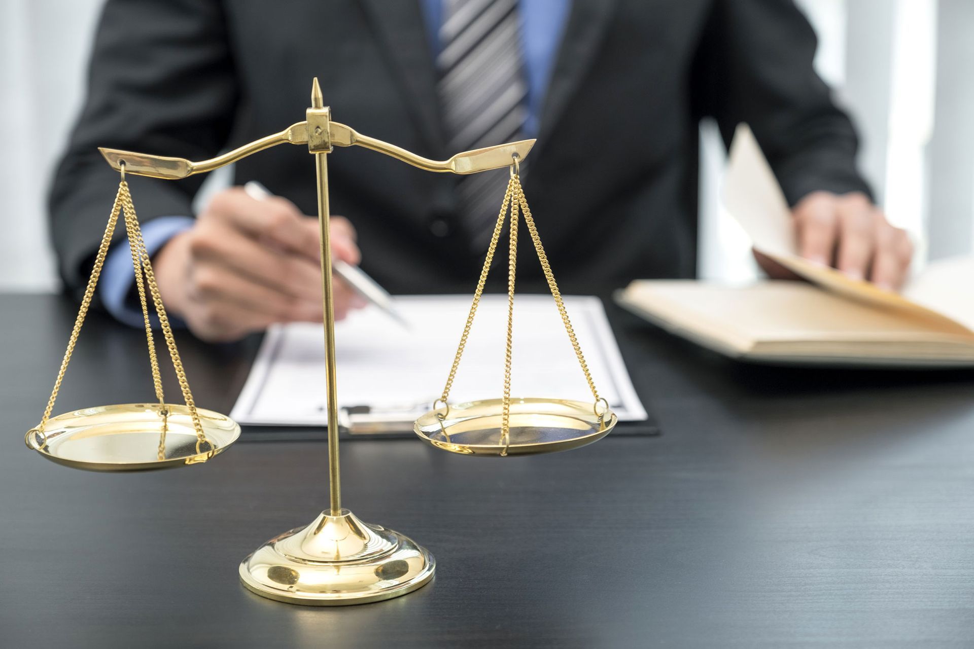 Scales of justice standing in front of the male lawyer providing service to client