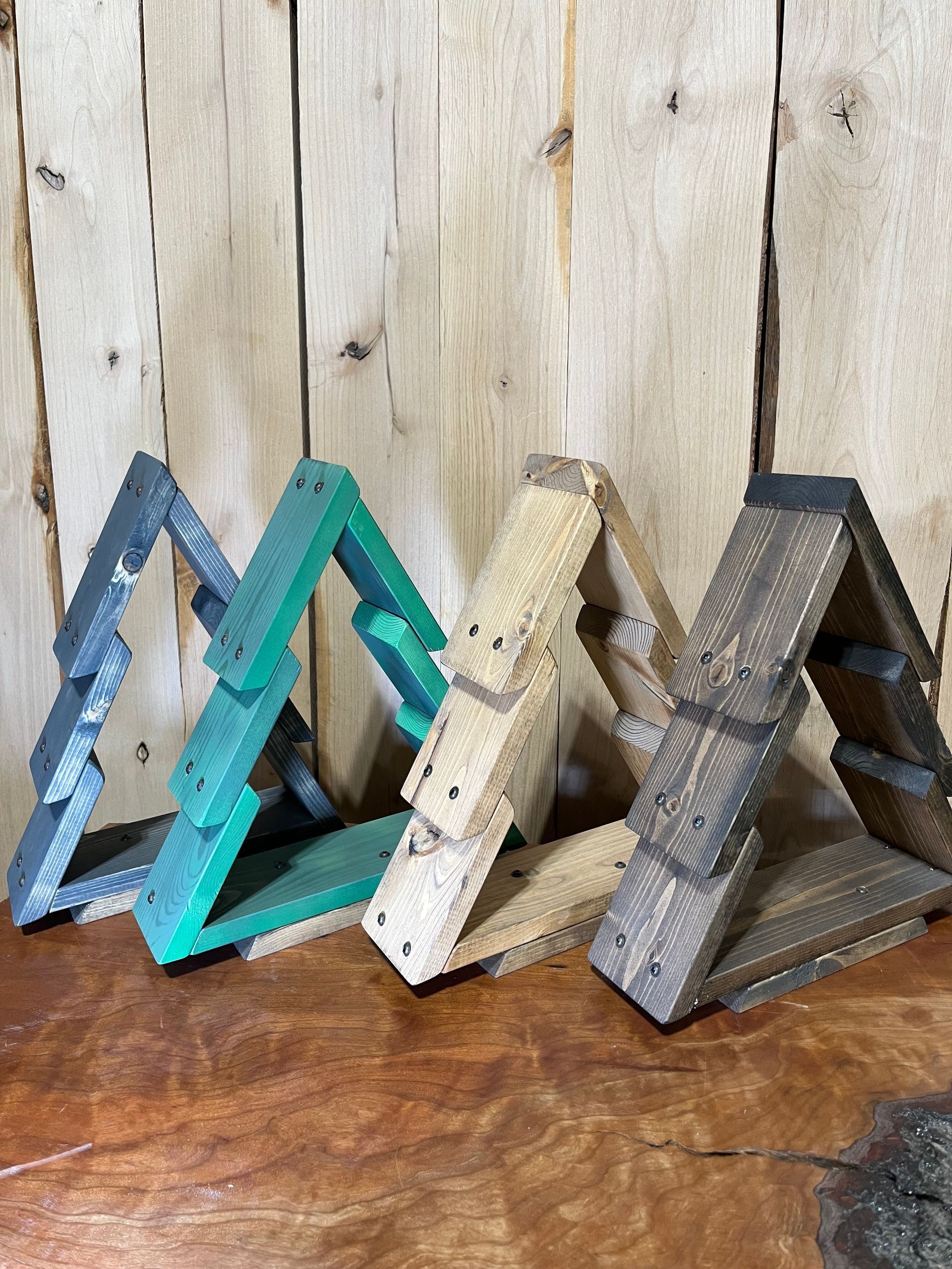 Three wooden triangles are sitting on a wooden table in front of a wooden wall.