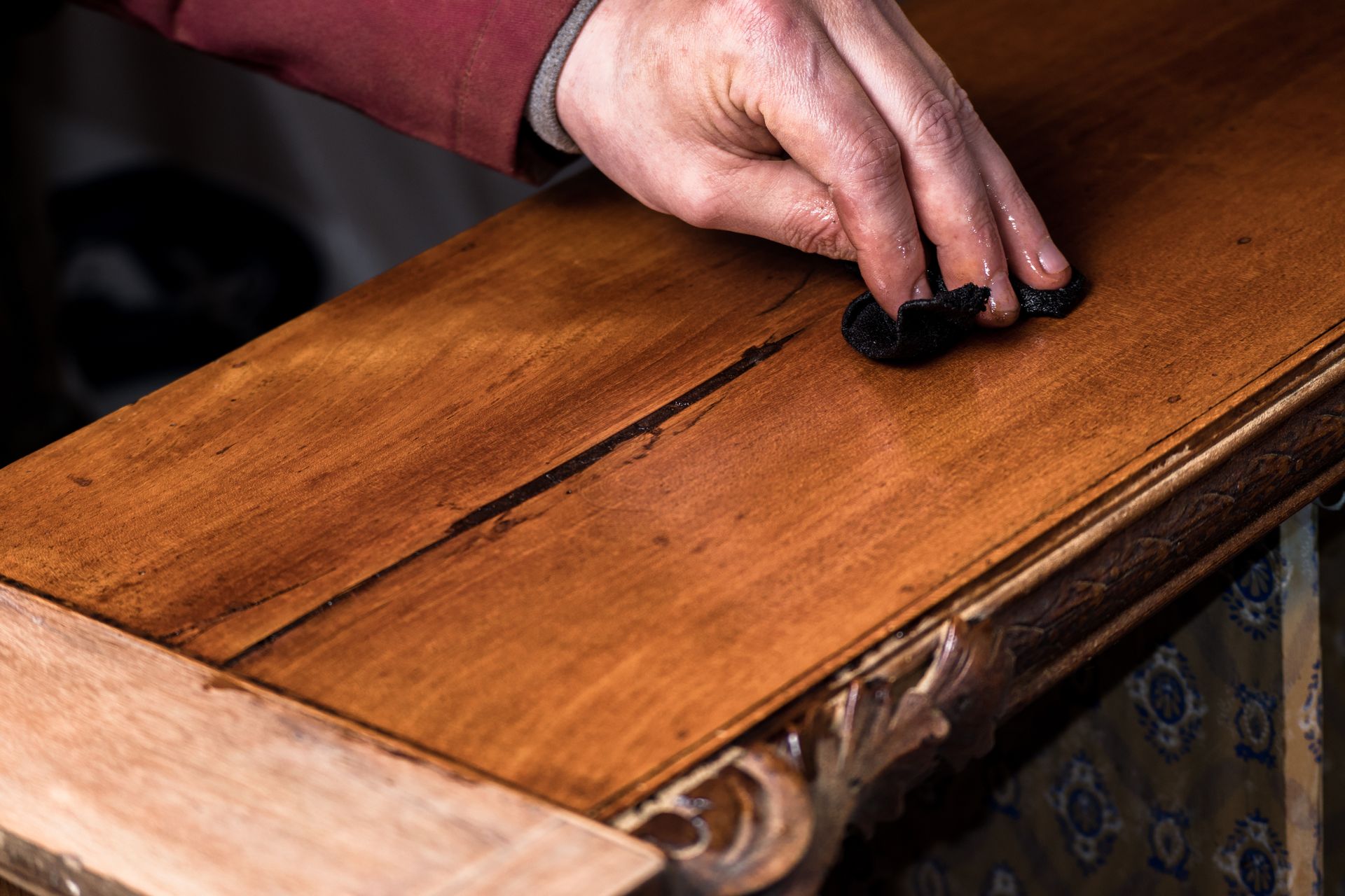 A person is polishing a piece of wood with their hands.