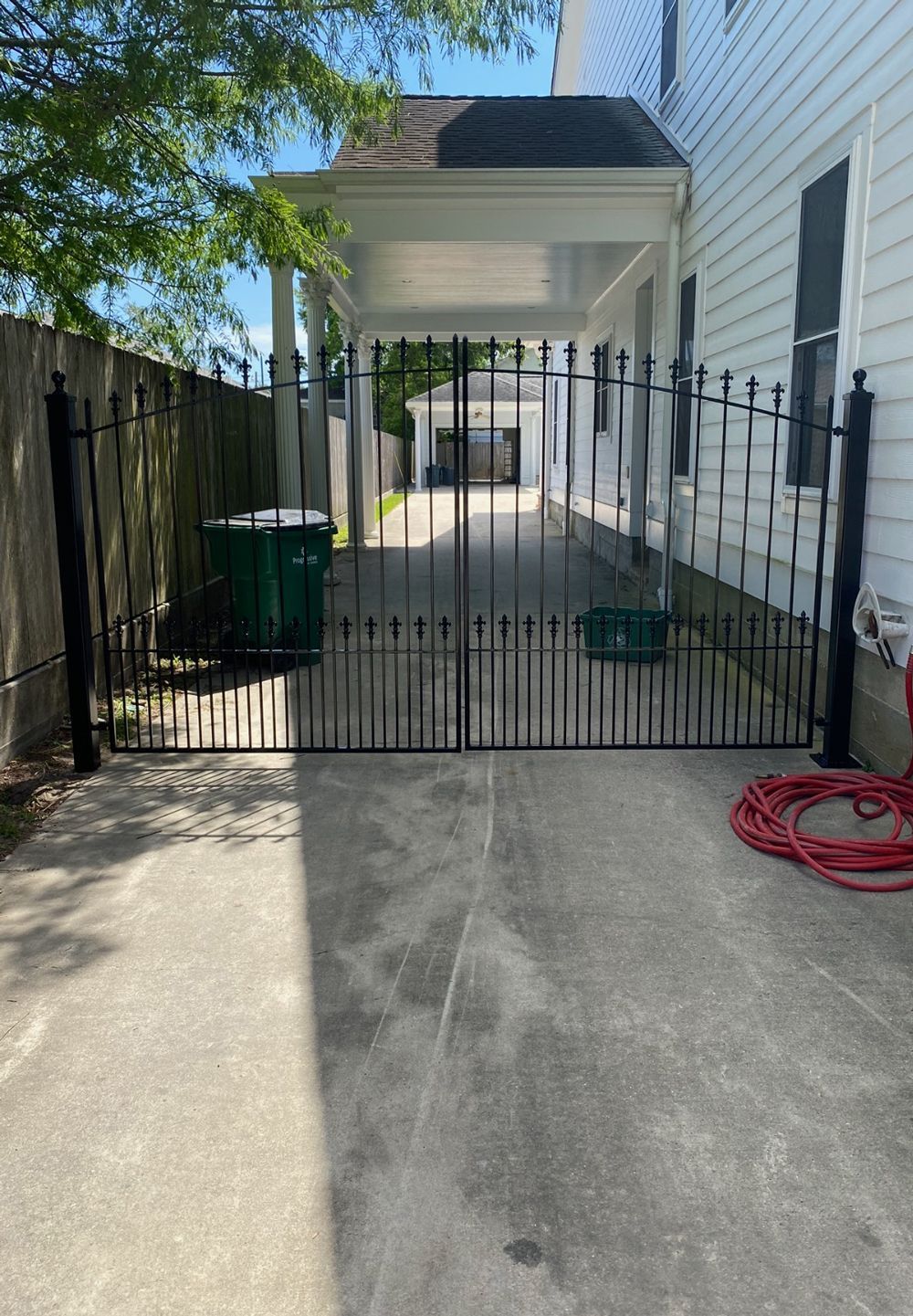 A black gate is sitting in front of a white house.