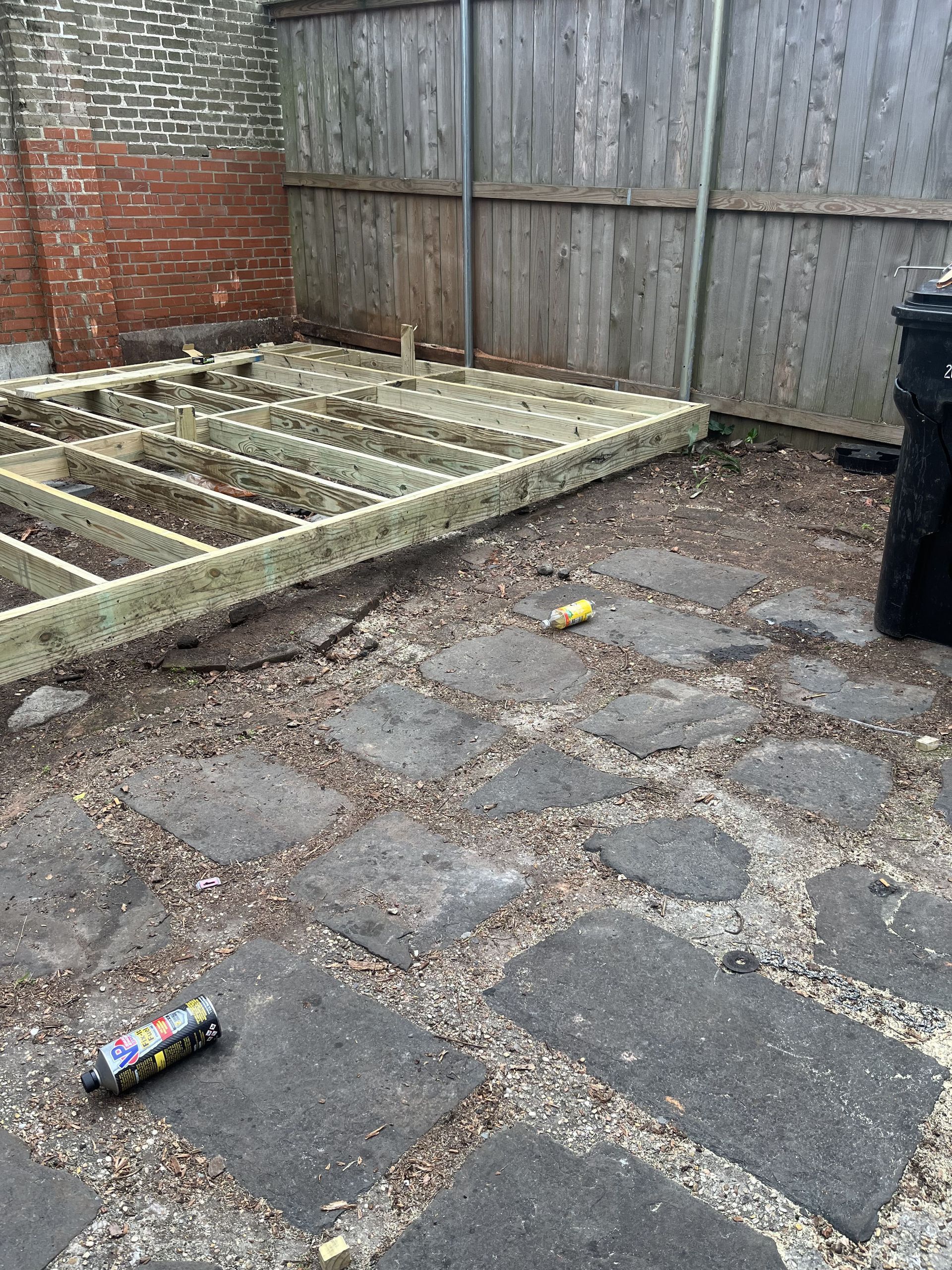 A wooden deck is being built in a backyard.