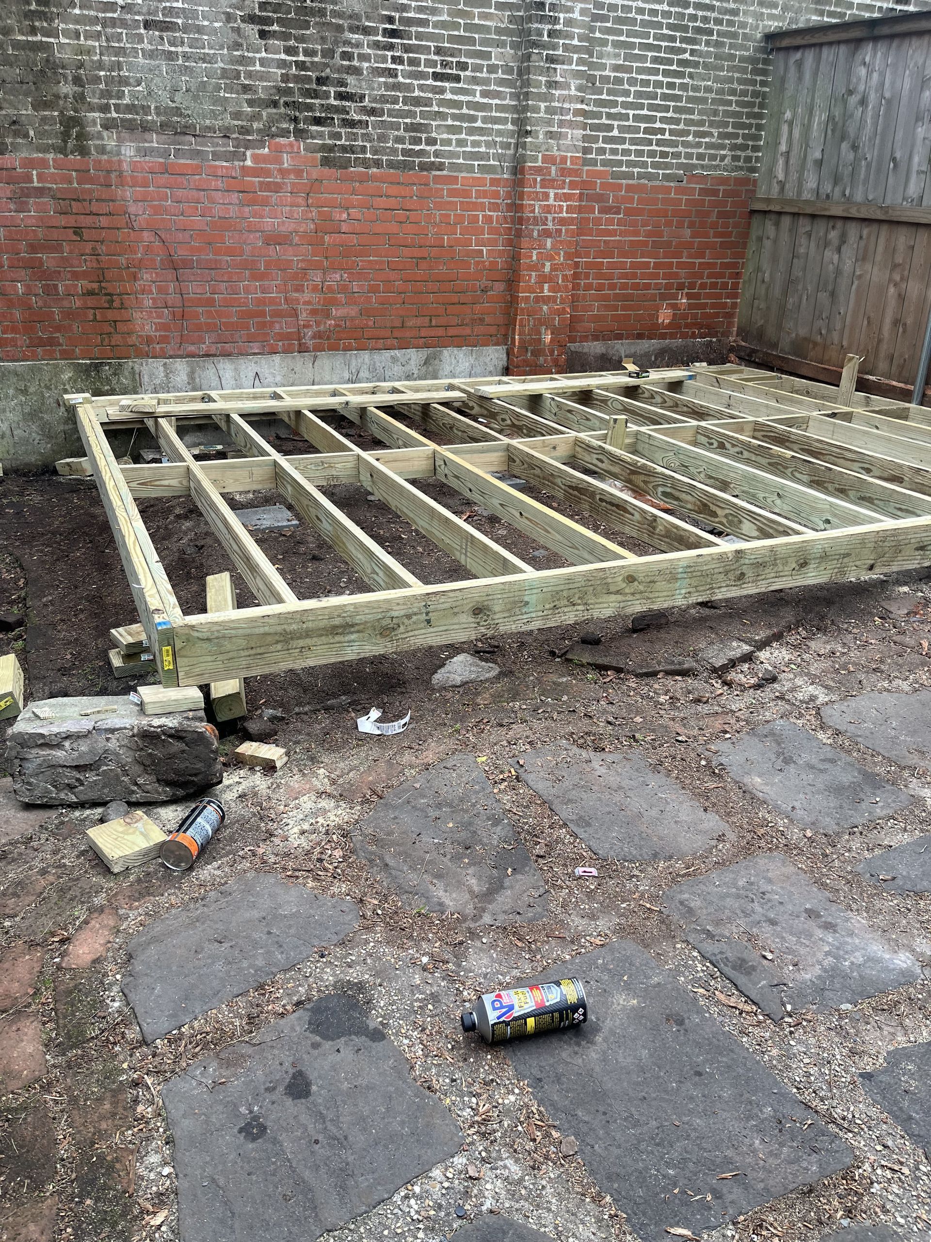 A wooden deck is being built in a backyard.