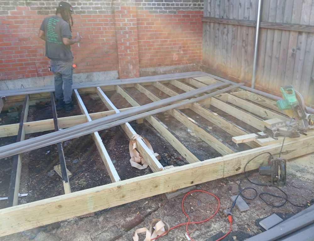 A man is standing on a wooden deck under construction.