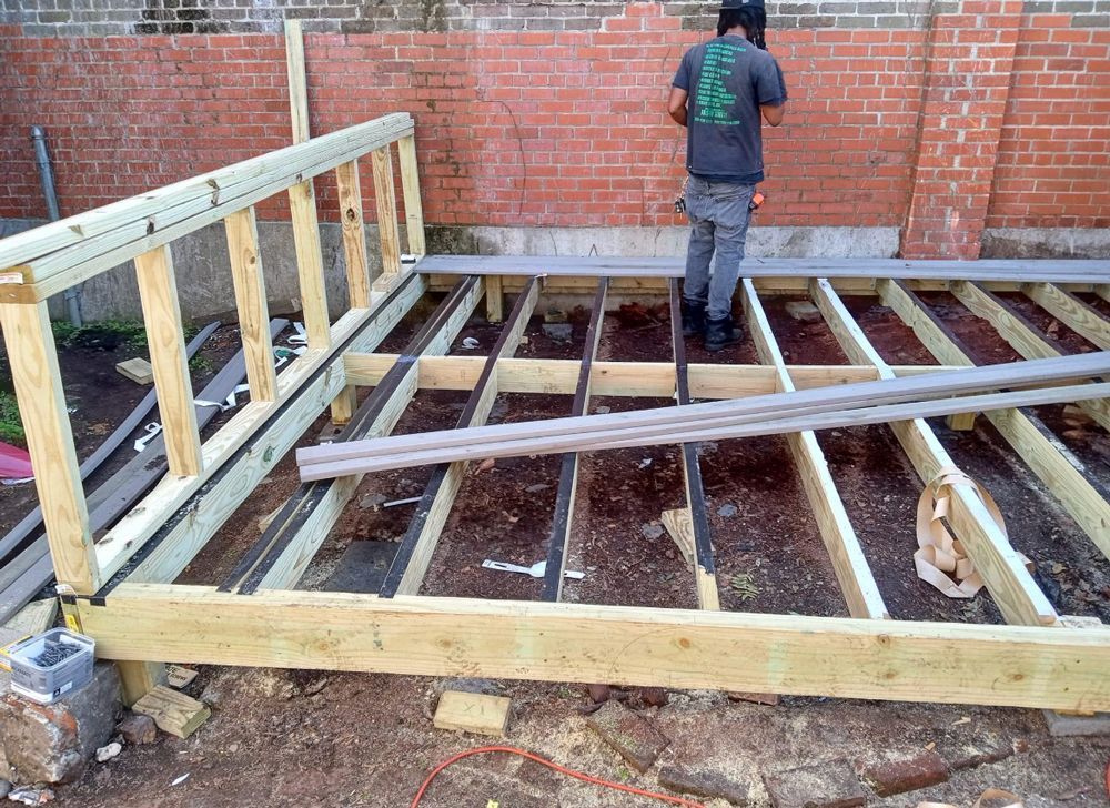 A man is standing on a wooden deck under construction.