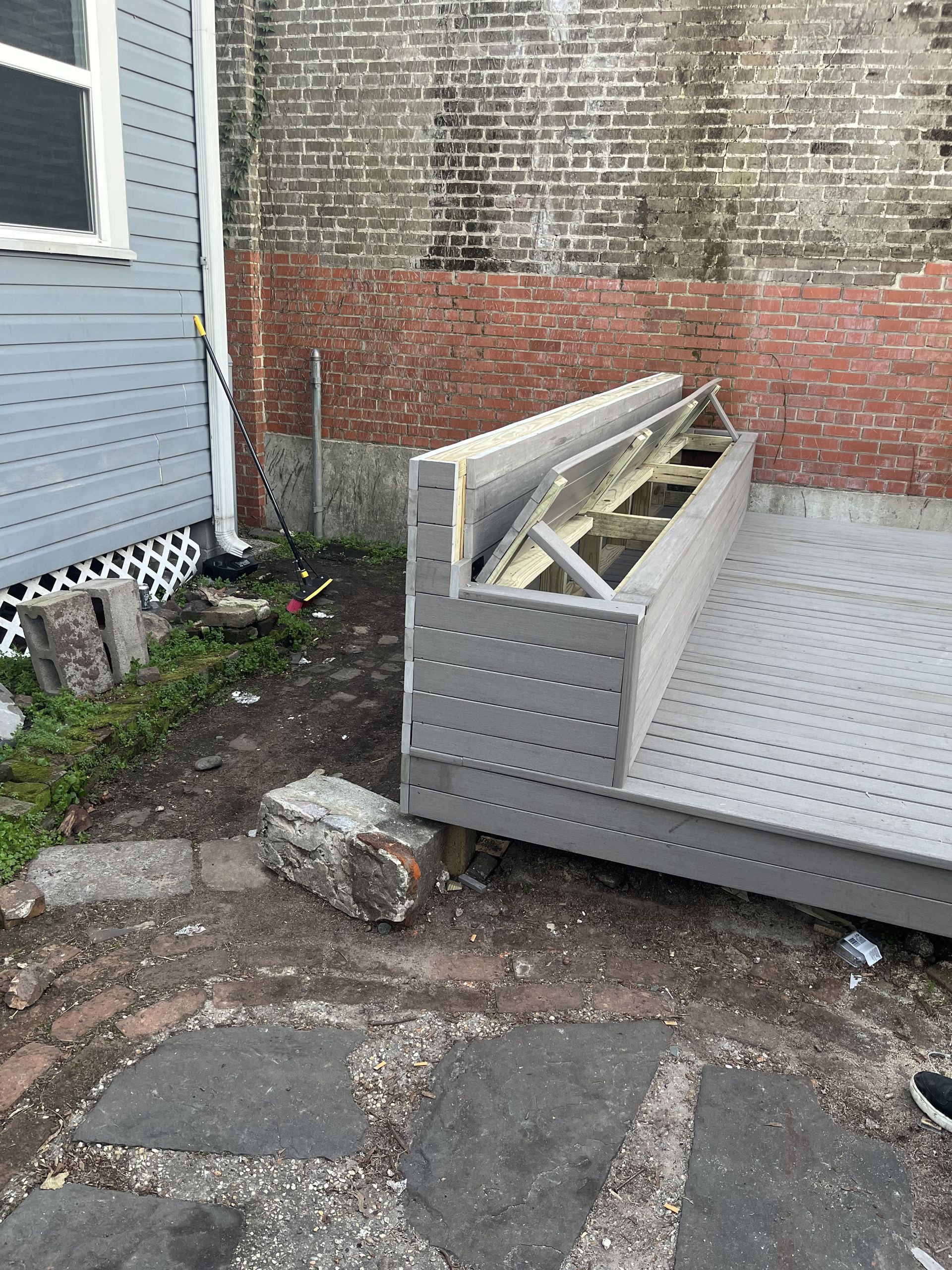 A couch is sitting on the ground in front of a brick wall.