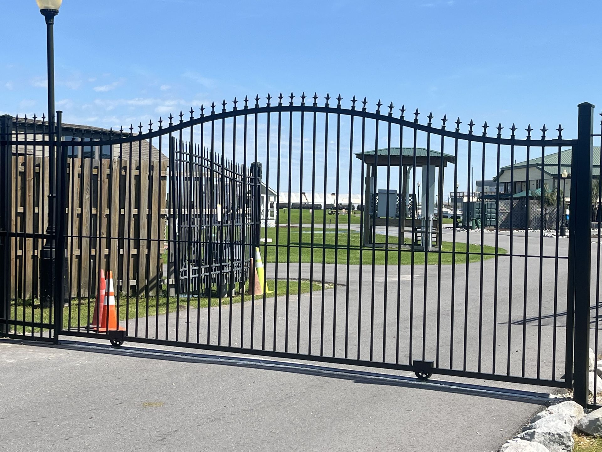 A black metal gate with a wooden fence in the background