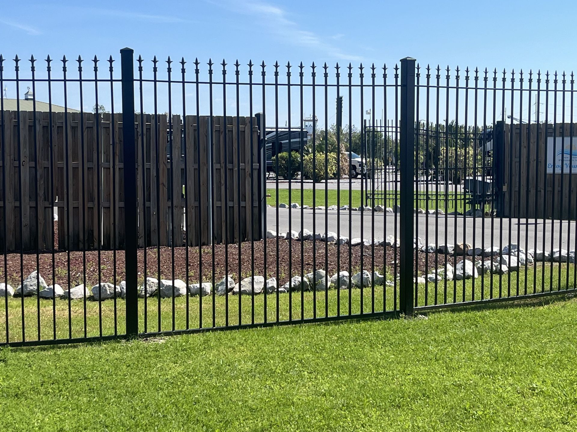 A black metal fence surrounds a lush green field.