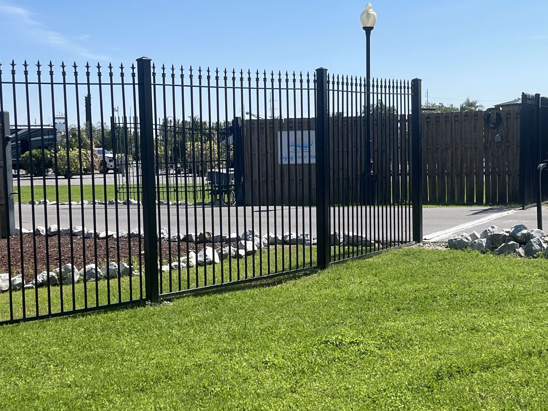 A black metal fence surrounds a lush green field.