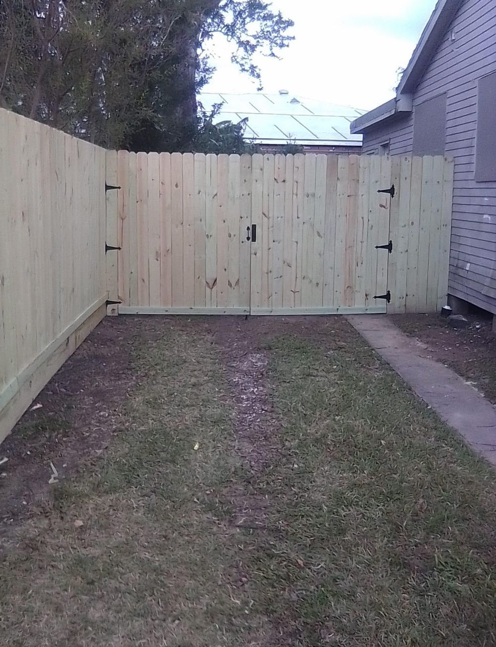 A wooden fence with a gate in the backyard of a house