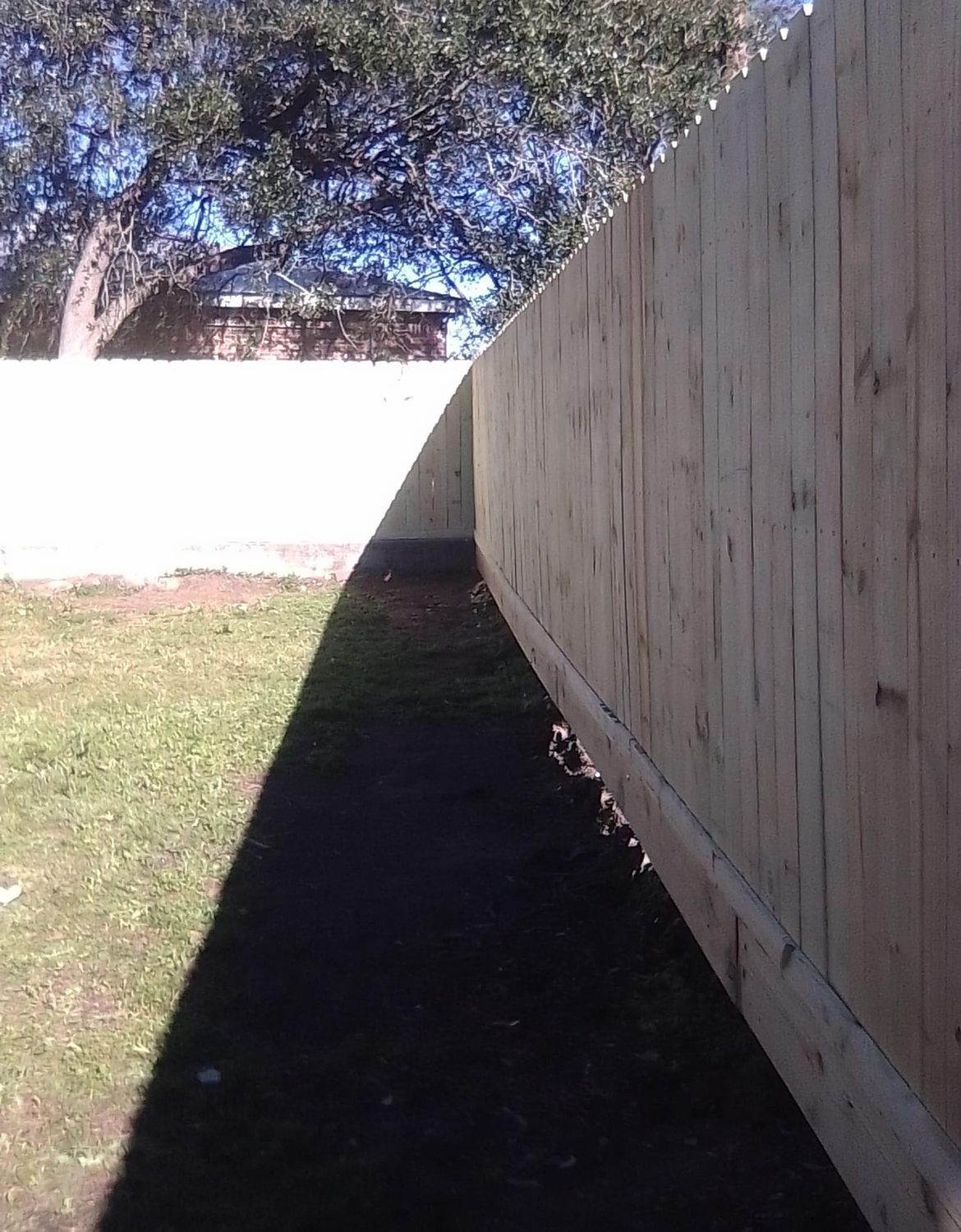 A wooden fence with a shadow on the ground