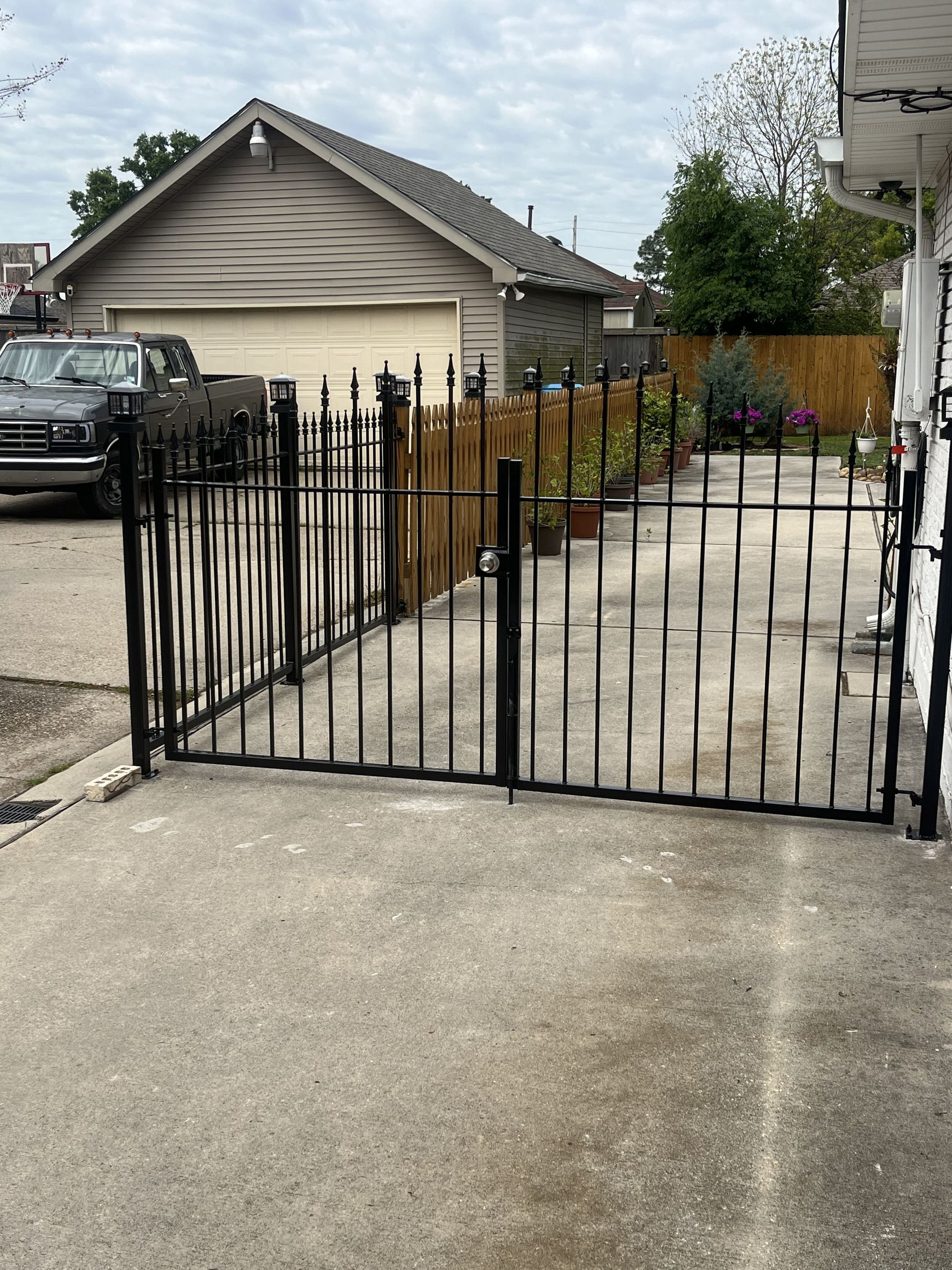 A car is parked in a driveway behind a wrought iron gate