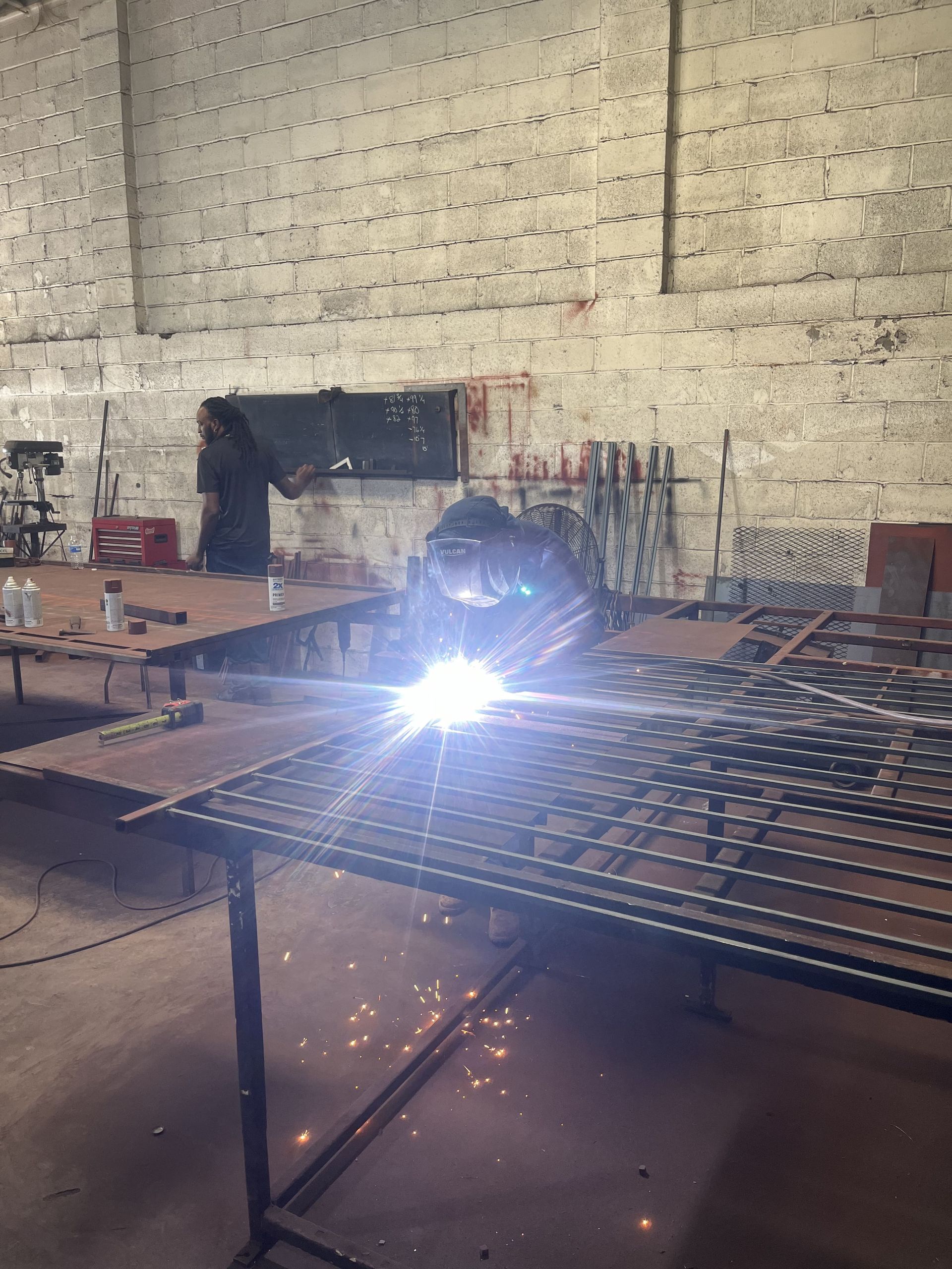 A man is welding a piece of metal in a warehouse.