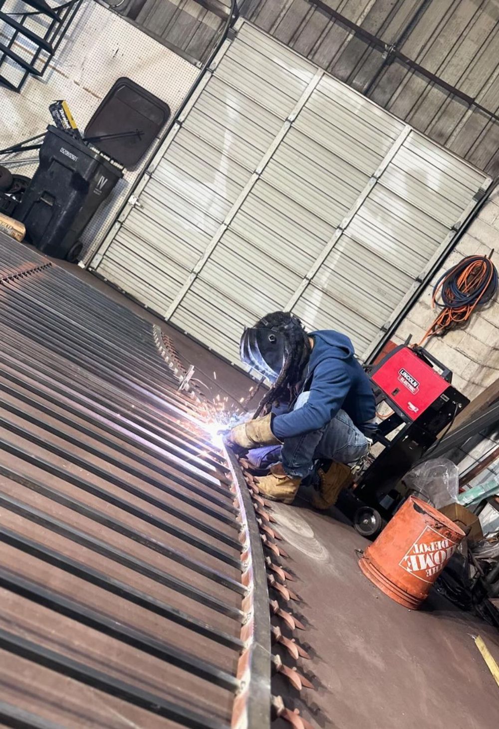 A man is welding a piece of metal in a garage.