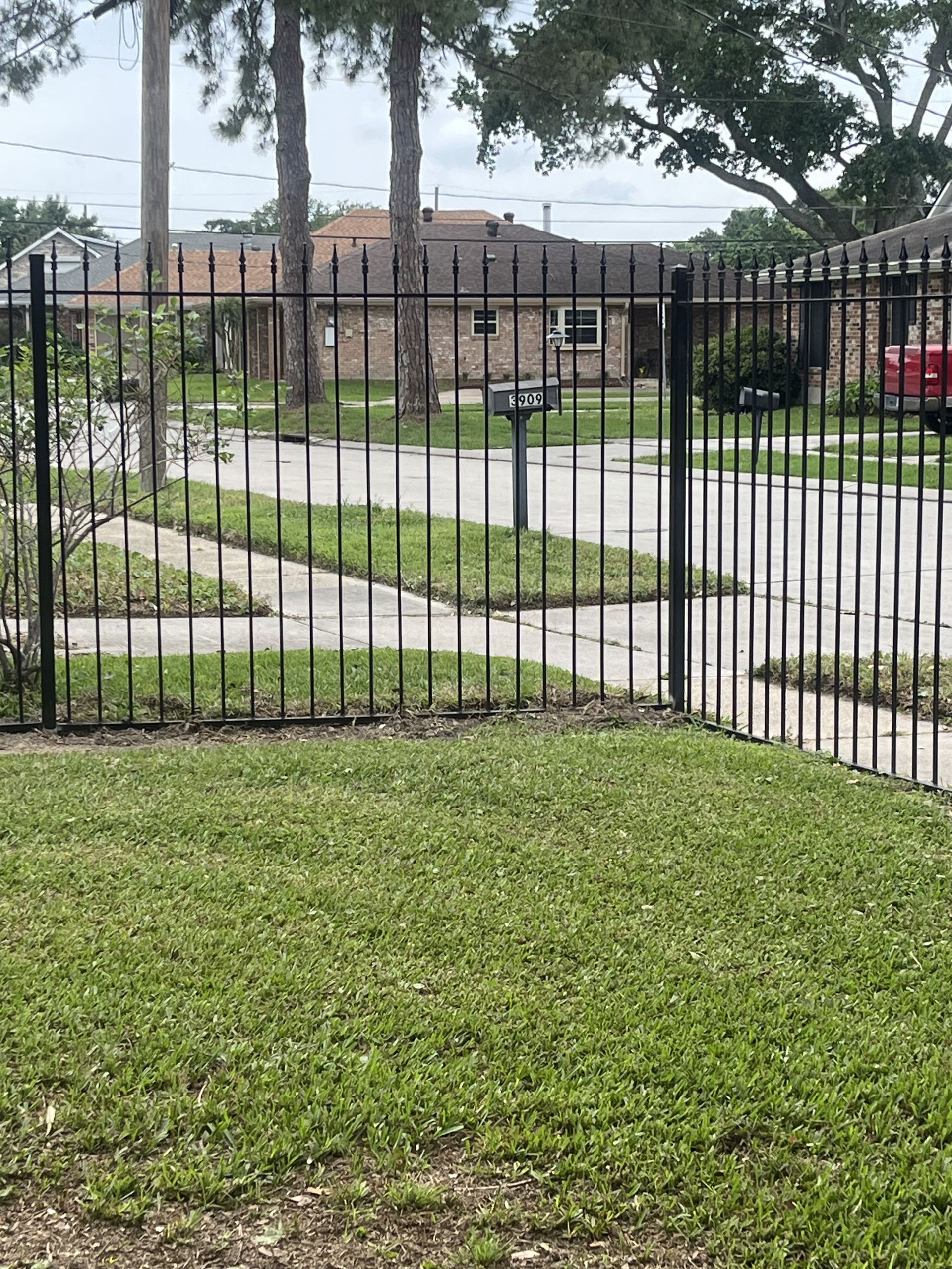 A black wrought iron fence surrounds a lush green yard.