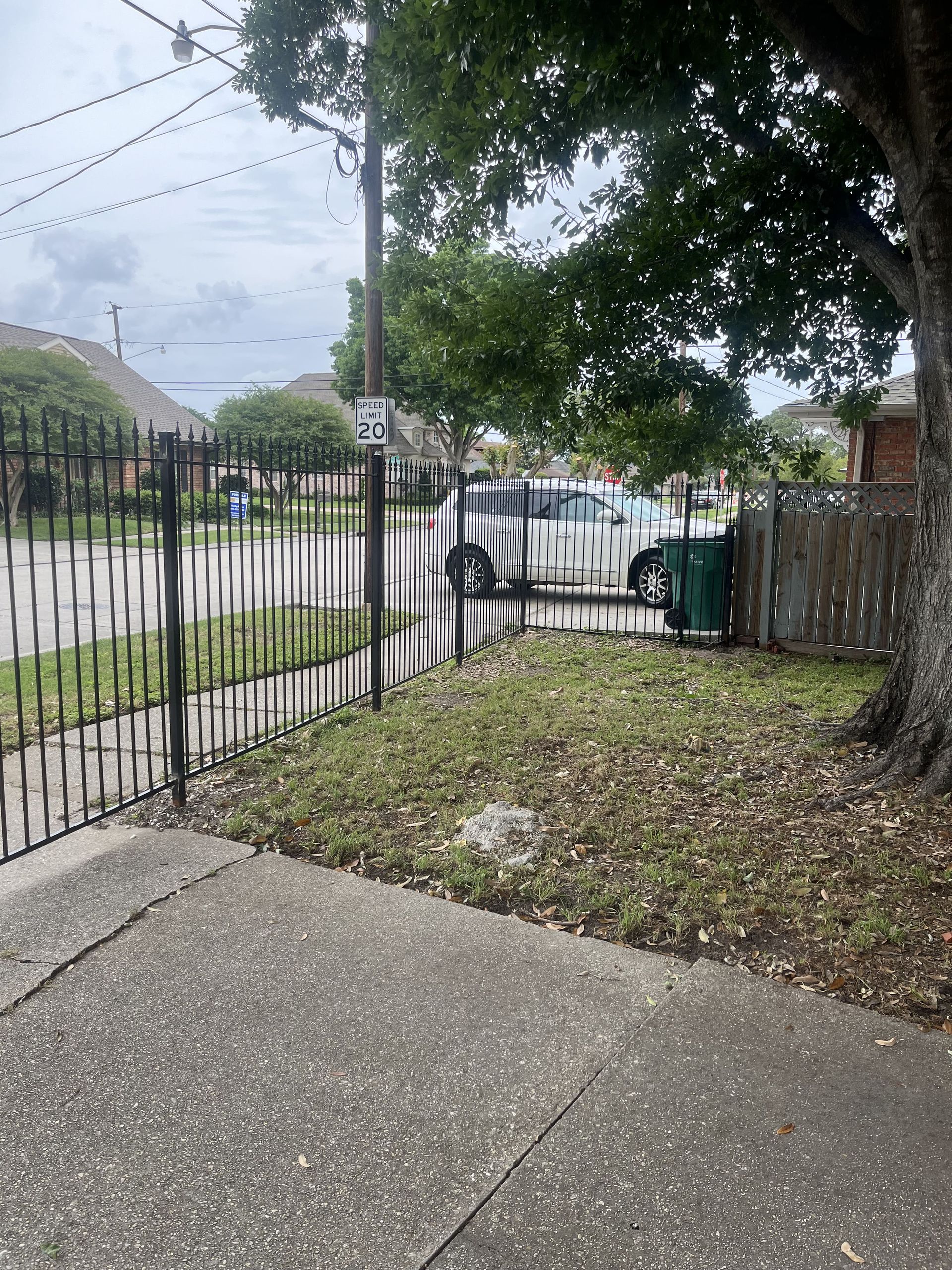 A wrought iron fence surrounds a lush green yard.