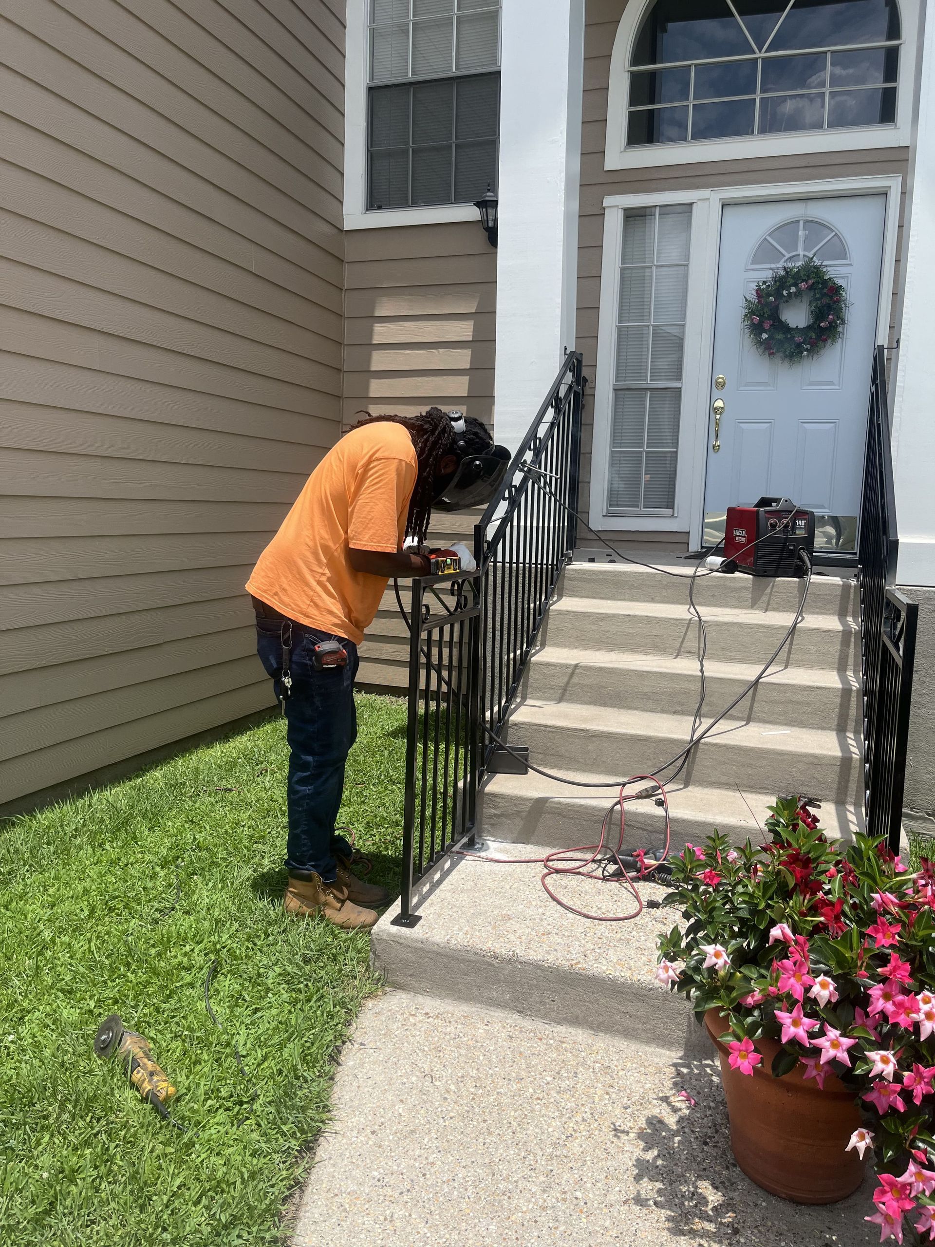 A man is welding a railing on the steps of a house.