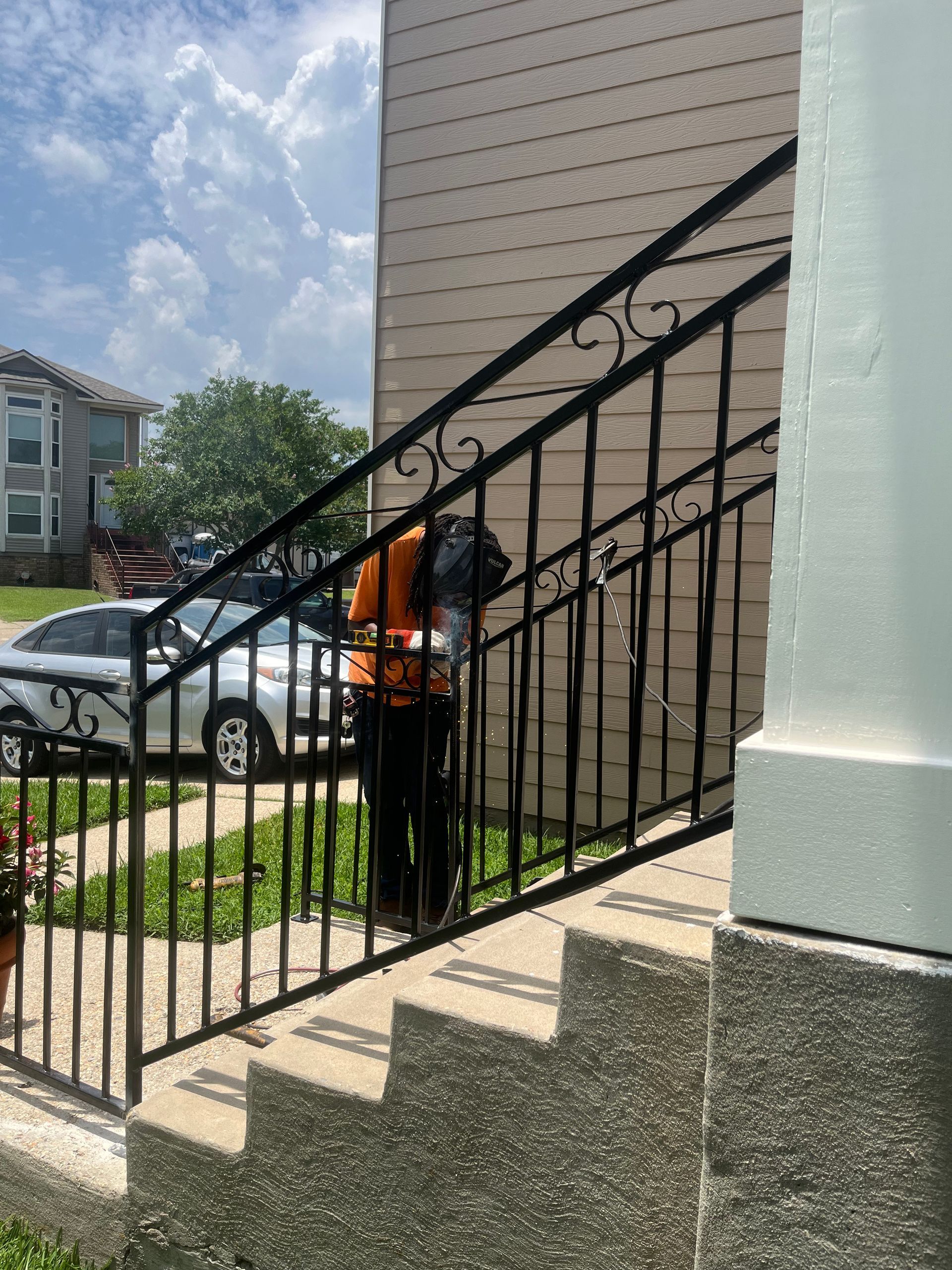 A person is standing on a set of stairs next to a wrought iron railing.