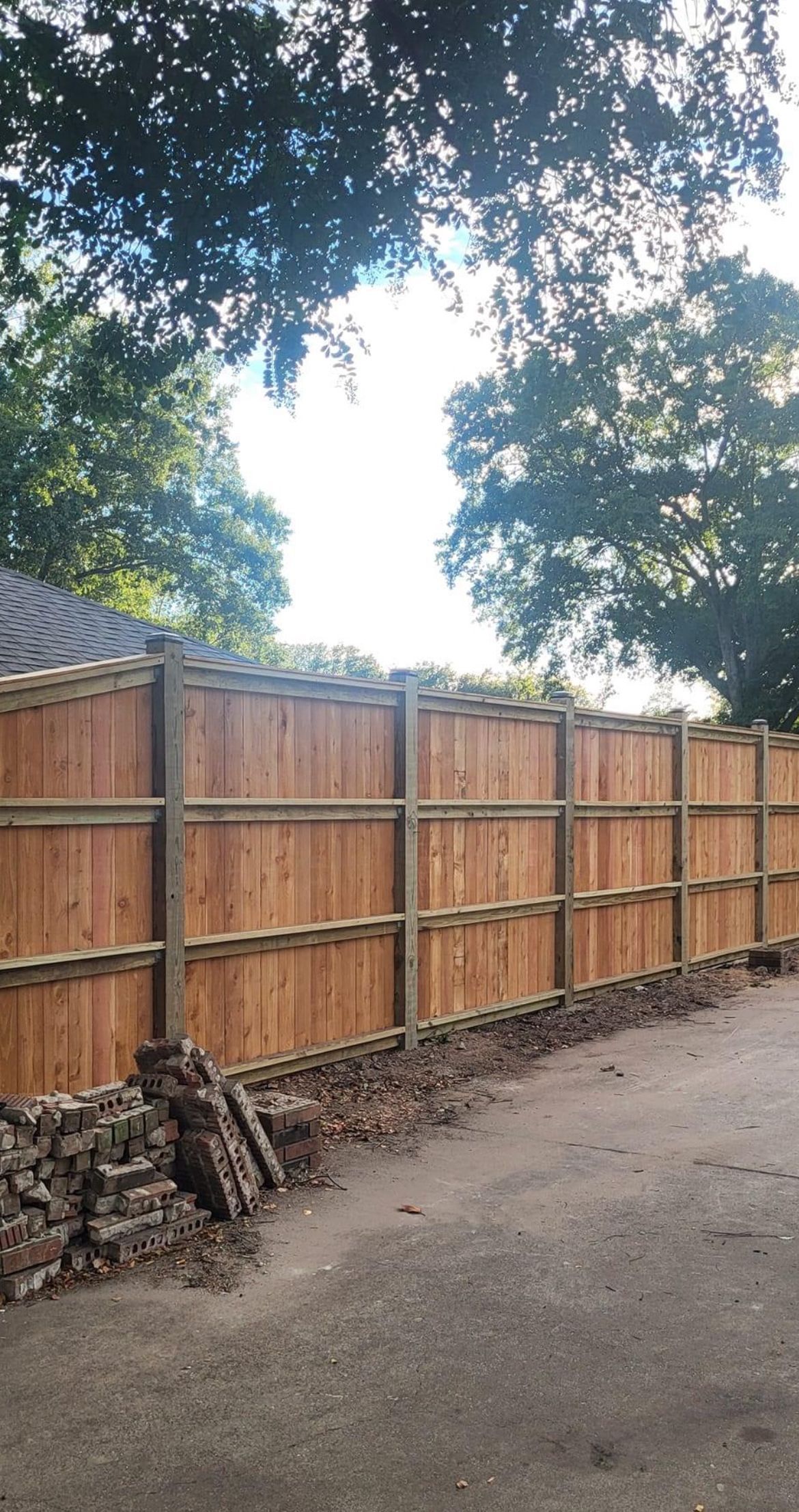 A wooden fence is being built next to a stone wall.