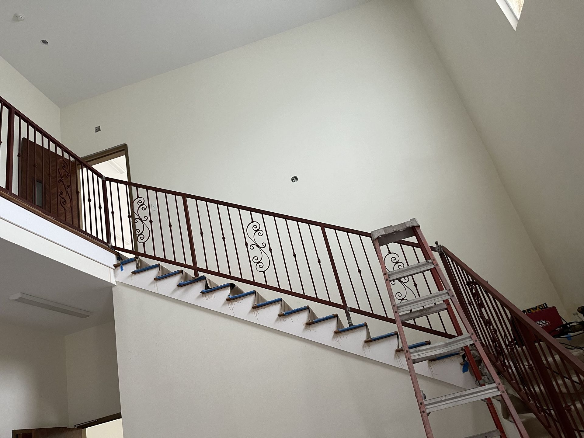 A ladder is sitting next to a staircase with a railing.