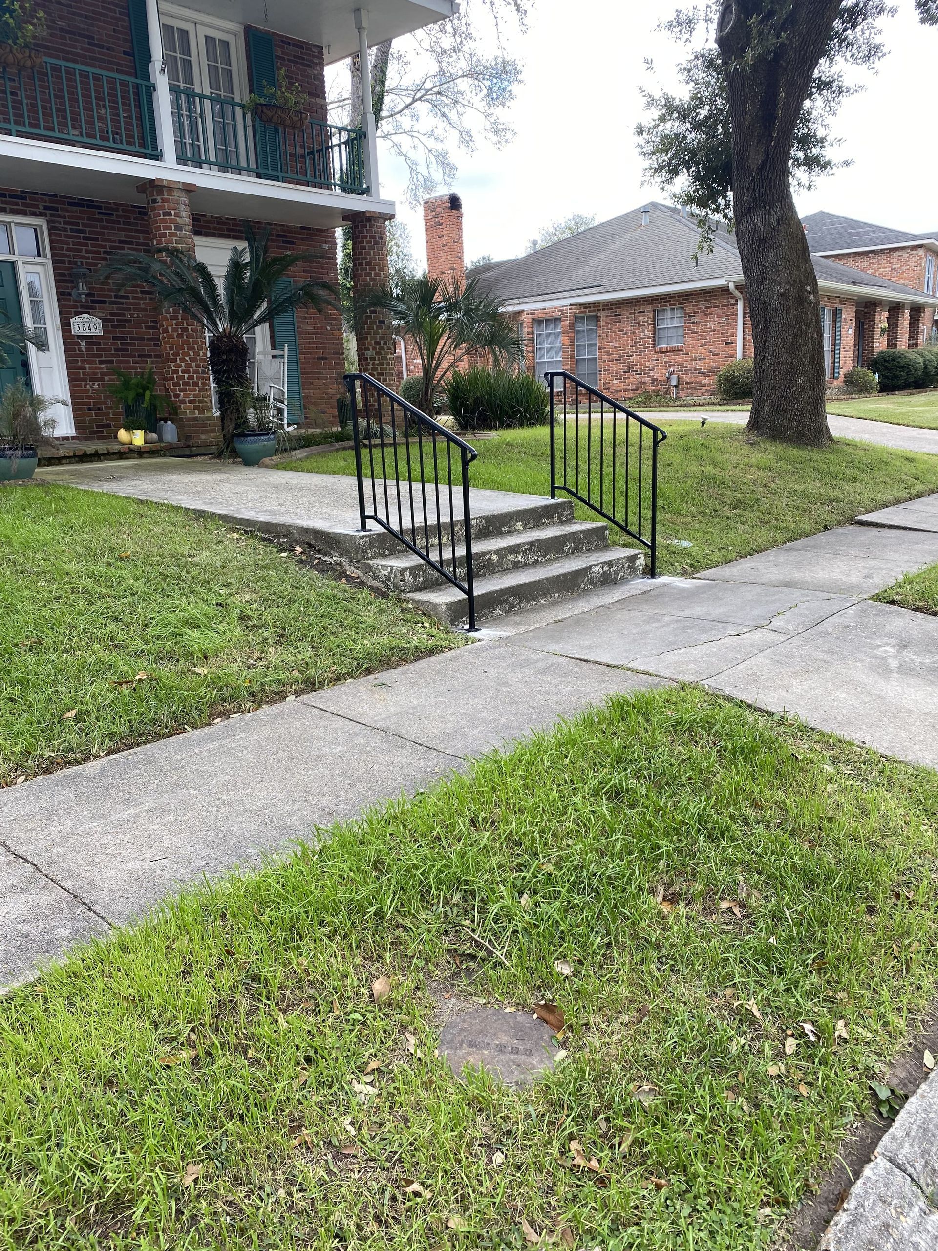 A brick house with a sidewalk and stairs in front of it.