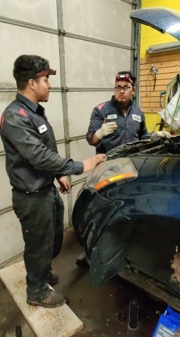 Two men are working on a car in a garage.
