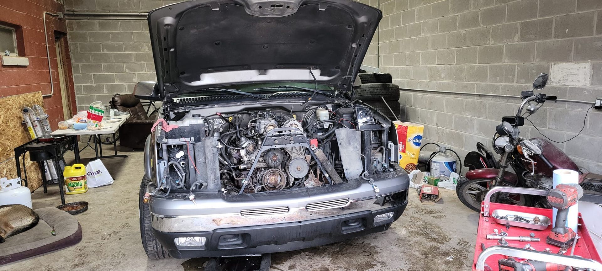 A truck with the hood up is sitting in a garage.