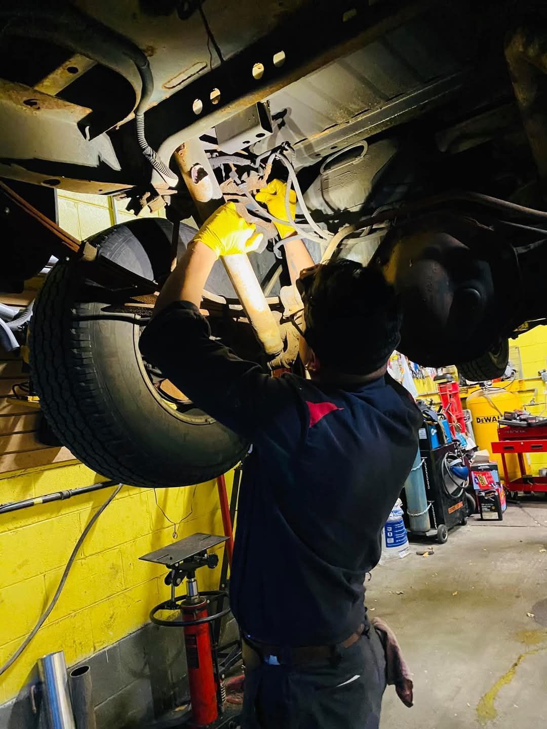 A man is working under a car in a garage.